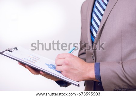 Close up view of a young businessman holding his clip board with charts isolated on white background. Writing progres down on a paper. Close-up of man's hand writing on a white paper. [[stock_photo]] © 