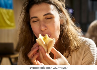 Close up view of young cute smiling female eating a hot slice of pizza. Adorable happy woman eating crispy pizza with cheese and pineapples.  Spending time with family or in a warm circle of friends.  - Powered by Shutterstock