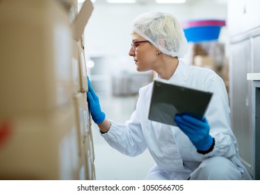 Close up view of a young female beautiful focused worker in sterile cloths inspecting a stack of boxes while holding the tablet. - Powered by Shutterstock