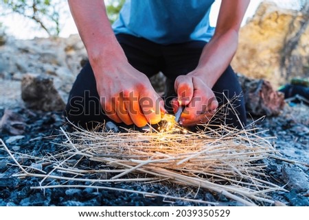 Close up view of a young male starting a fire with flint and steel outside. Survival concept.