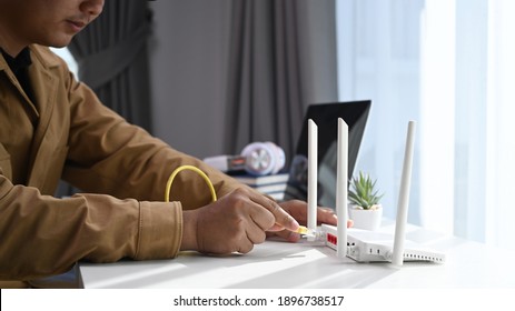 Close Up View Of Young Man Connects The Internet Cable Into Router Wireless At Home.