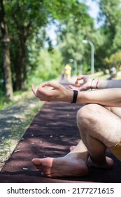 Close Up View To Young Man Meditating Outdoors In The Park, Sitting On The Road In The Lotus Position. Vertical View