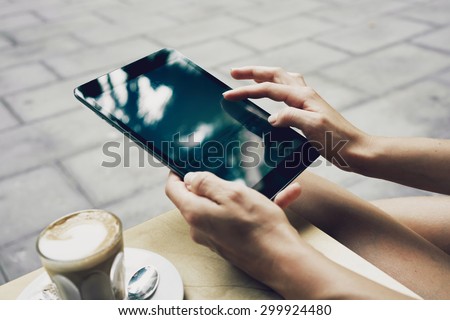 Close up to view young woman's hands hold tablet with empty screen. woman writing email during the coffee break