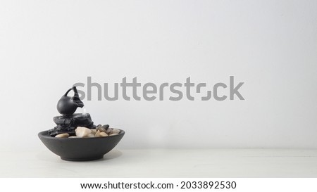   Close view of a zen water fountain over a white wooden table with a white background                               