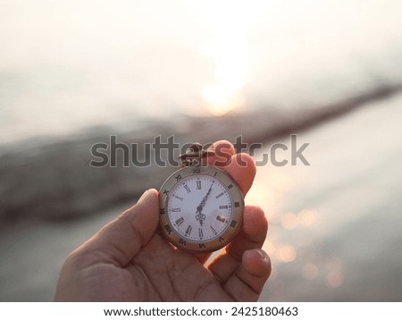 Close up of vintage pocket watch in woman hand with sea in the sunset time as background.