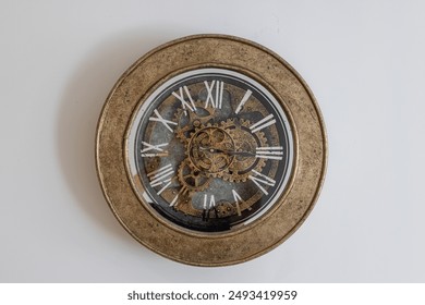 Close up of a vintage wall clock featuring Roman numerals and intricate gears, set against a plain white background.
 - Powered by Shutterstock