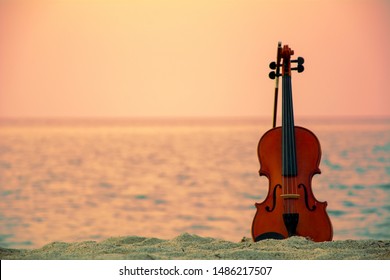 Close up of a Violin at the beach with sunset background