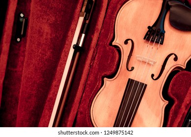 Close up of a violin shallow deep of fieldViolin and bow in dark red case.  Close view of a violin strings and bridge