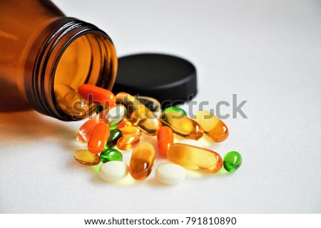 Close up vitamins and supplements on white background with a brown bottle. Including Vitamin c, vitamin E, vitamin D3, salmon oil, fish oil and co enzyme Q10 capsules.