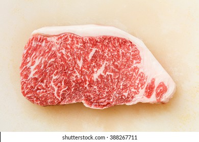 Close up wagyu beef striploin steak on dirty plastic cutting board