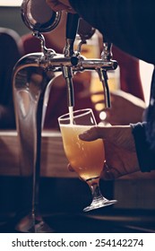 Close Up Of Waitress Hands Pouring Beer Into Glass