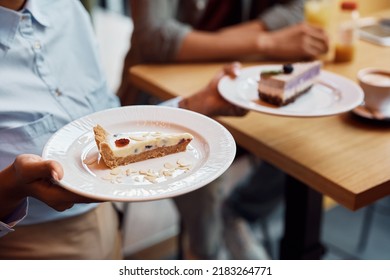 Close up of waitress serving a slice of cake to her customers in cafe. 