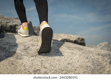 close up of walker climbing over rocks. Walking shoes, trainers. - Powered by Shutterstock