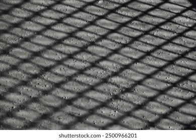 The close up of a walkway on a pedestrian bridge whose railings throws shadows - Powered by Shutterstock