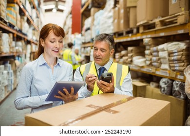 Close up of warehouse managers looking at tablet pc in a large warehouse - Powered by Shutterstock