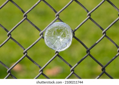 Close up water bottle with droplets inside stuck in a silver wire fence against green backdrop - Powered by Shutterstock