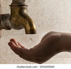Close up of water dropping from a brass metal tap on a human hand