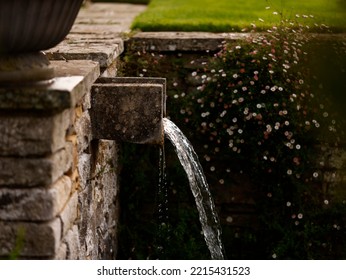 Close Up Of A Water Feature In The Garden With Water Running From An Extended Ledge Coming Out Of A Wall.