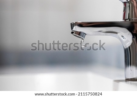 Close up of a water tap with a droplet falling.