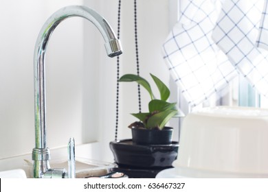 Close up water tap with sink in modern kitchen.