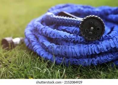 close up of watering hose lies on the grassy ground. blue rubber tube with device for spraying and watering plants in the garden. selective focus