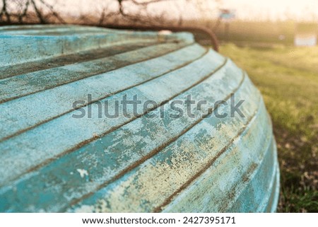 Close up of the weathered, turquoise surface of an old wooden boat on the shore in the light of the sunset. Selective focus.