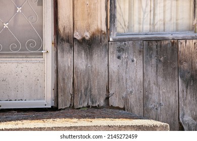 Close Up Of Weathered Wood Siding Beginning To Rot Around Front Step Of Cottage Or House