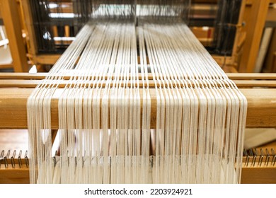 close up of weaving machine. A loom machine for clothing or woven label. Weaving machine for garment industry. Yarn thread lines on the weaving loom machine for clothing in textile factory. - Shutterstock ID 2203924921