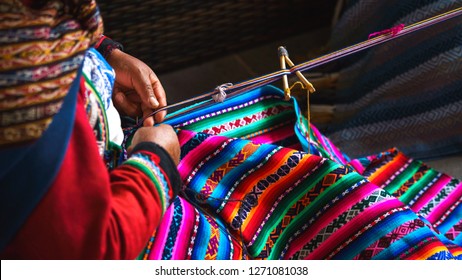 Close up of weaving in Peru. Cusco, Peru   woman dressed in colorful traditional native Peruvian closing knitting a carpet with national pattern. Classic Blue Color of the year 2020 concept.