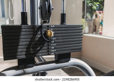 Close up of weight plates machine with yellow pin in the gym.