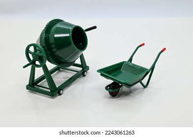 Close up of a wheelbarrow and a cement mixer. An image of a construction site. - Shutterstock ID 2243061263