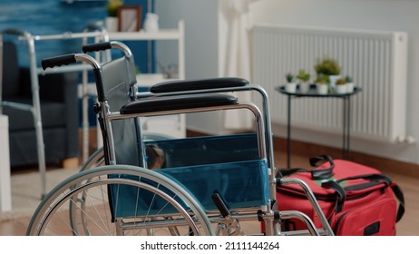 Close Up Of Wheelchair For Transportation Support And Medical Bag On Floor Of Nursing Home. Chair Used For Accessibility And Handbag Filled With Equipment And Tools For Healthcare.