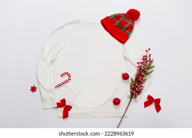 Close up white blank template sweatshirt copy space. Christmas Holiday concept. Top view mockup sweatshirt, hat. Red holidays decorations on white background. Happy New Year accessories. Xmas outfit