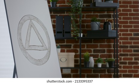 Close Up Of White Board With Aa Meeting Sign In Office. Space With Furniture And Anonymous Alcoholics Symbol On Display, Room Used For Therapy Session And Rehabilitation Program.