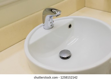 Close up of white ceramic wash sink and stainless steel faucet in public bathroom