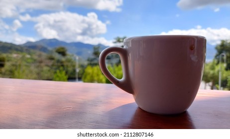 Close Up Of White Coffee Cup On Wooden Table, Side View On Blurred Background