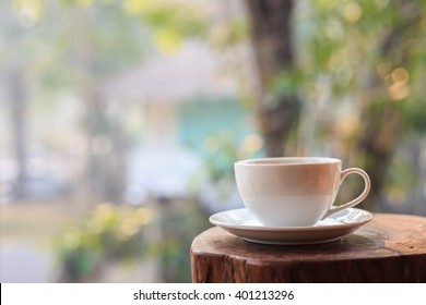 Close Up White Coffee Cup On Table In Garden With Blur Light Bokeh