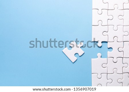close up white color a part of jigsaw on blue color background and one part out of group with concept