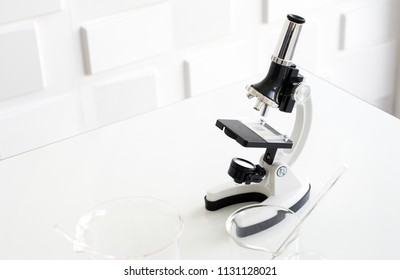 Close up of white microscope in science laboratory on white table. Microscope for chemistry, biology, test, samples, examining, medical, equipment and education.