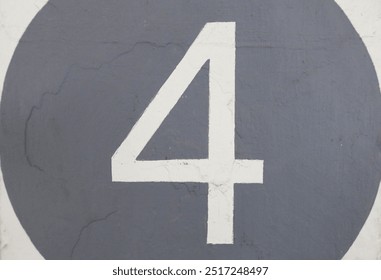 close up of white number four (4) in a grey circle on the white wall