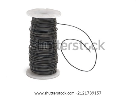Close up of a white plastic roll with dark metal wire wound on it and a rolled protruding end on white background