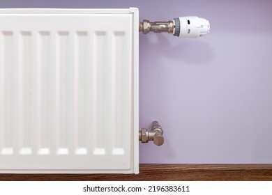 Close Up Of White Radiator Thermostatic Brass Valve And Angled Pipes On The Light Shade Of Pastel Color Painted Wall. Central Heating Installation, Warm Home.