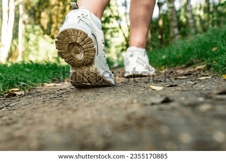 Close up of white running shoes from behind on forest background.