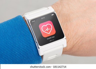 Close Up White Smart Watch With Health App Icon On The Screen Is On Hand