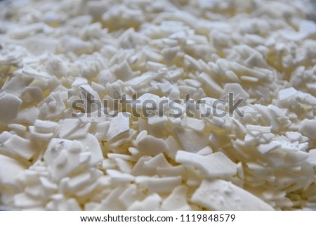 Close up of white soy wax flakes for candle making in a ceramic bowl.