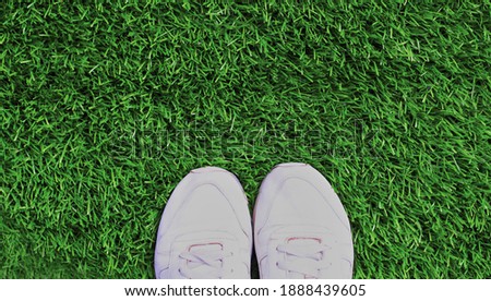 Close up white sports sneakers on a green grass background, blank copy space