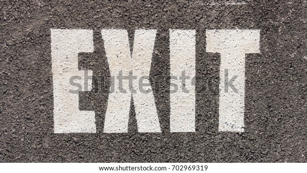 close up of white traffic exit sign\
on asphalt in a parking area in the city for traffic\
rule