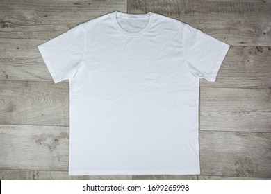 Close up of white t-shirt on the wooden table. Blank t-shirt for add your text, design, symbol, template