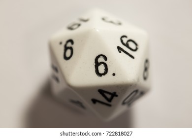 Close up of a white twenty-sided die, top-down view, with the number six showing.