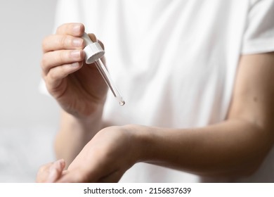 Close Up Of White Woman Hand Applying Oil Of Essential Oil Or Serum For Skin. Self Care Concept 